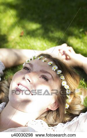 Woman lying on grass wearing daisy chain View Large Photo Image Stock Photo - Woman lying on grass wearing daisy chain. Fotosearch