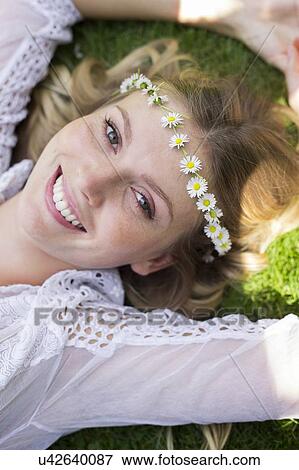 Stock Photo - Woman lying on grass wearing daisy chain. Fotosearch