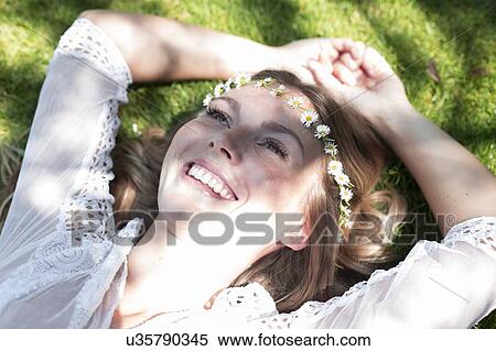 Stock Photography - Woman lying on grass wearing daisy chain. Fotosearch