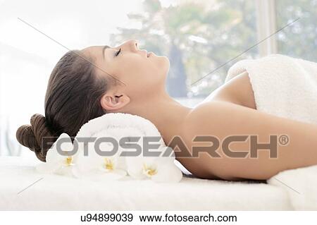 Stock Photo - Woman lying on towel in spa. Fotosearch