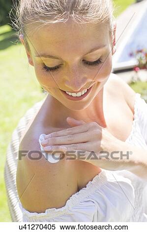 Stock Photography - Woman rubbing sun cream on shoulder. Fotosearch