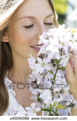 Stock Photo - Woman smelling white flowers. Fotosearch