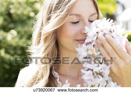 Stock Photo - Woman smelling white flowers. Fotosearch