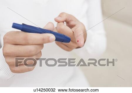 Stock Image - Woman testing glucose. Fotosearch