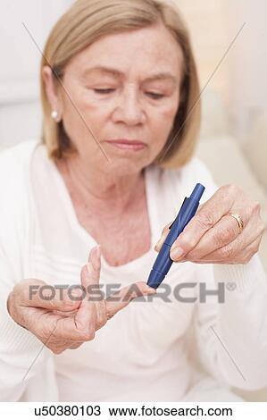 Stock Image - Woman testing glucose. Fotosearch