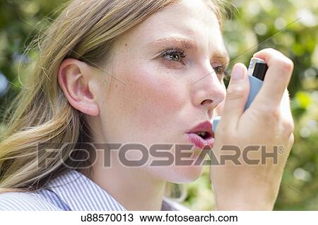 Stock Image - Woman using inhaler. Fotosearch
