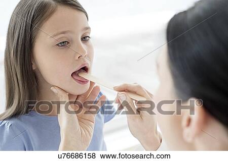 Stock Photo - Female doctor examining inside girl's mouth. Fotosearch