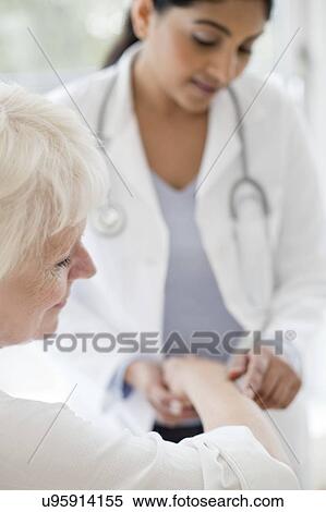 Stock Photography - Female doctor examining patient's arm. Fotosearch