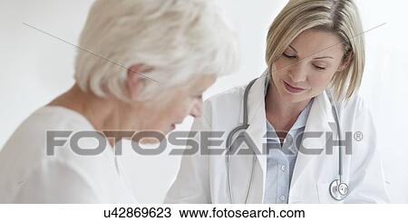 Stock Image - Female doctor examining senior patient. Fotosearch