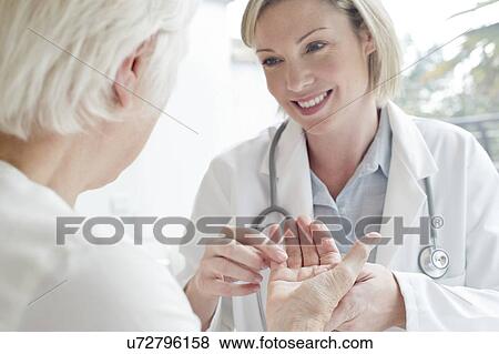 Stock Photo - Female doctor examining senior patient's hand. Fotosearch