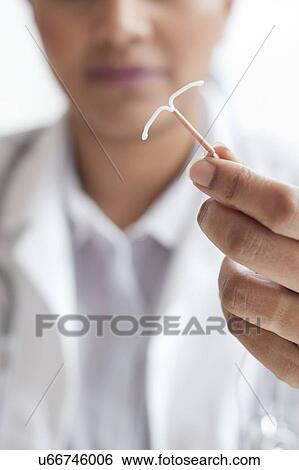 Stock Photograph - Female doctor holding an IUD. Fotosearch