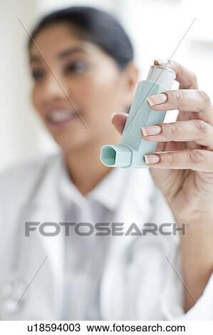 Stock Image - Female doctor holding inhaler. Fotosearch