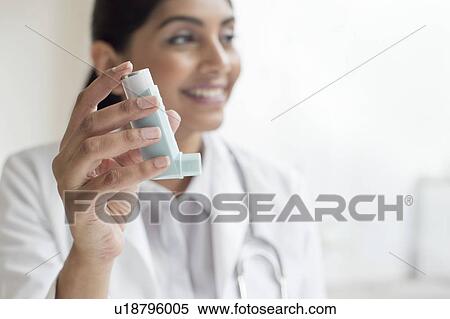 Stock Photography - Female doctor holding inhaler. Fotosearch