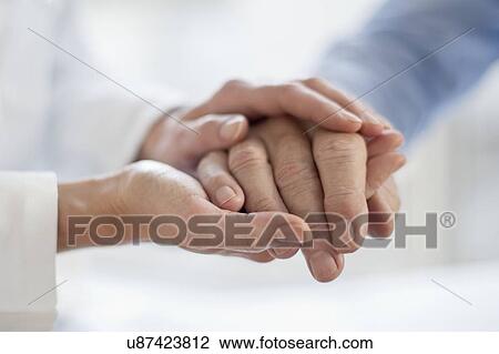 Stock Image - Female doctor holding patient's hand. Fotosearch