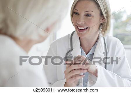 Female doctor smiling towards patient View Large Photo Image Stock Image - Female doctor smiling towards patient. Fotosearch
