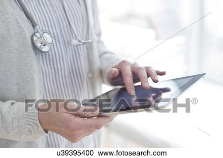 Stock Image - Female doctor using tablet. Fotosearch