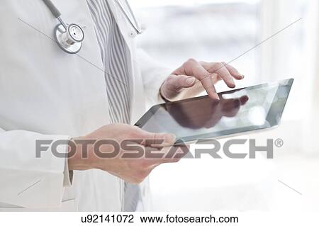 Stock Image - Female doctor using tablet. Fotosearch