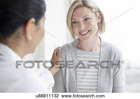 Stock Image - Female doctor with hand on patient's shoulder. Fotosearch