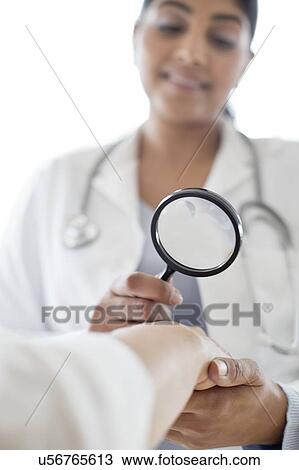 Stock Image - Female doctor with magnifying glass. Fotosearch