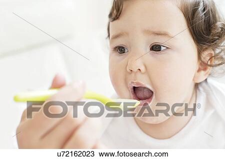 Stock Image - Female toddler being spoon fed. Fotosearch