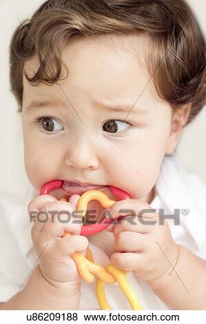 Stock Photo - Female toddler chewing rattle. Fotosearch