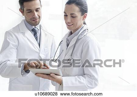 Stock Photo - Male and female doctors using tablet. Fotosearch