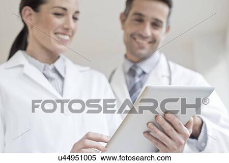 Stock Photography - Male and female doctors using tablet. Fotosearch