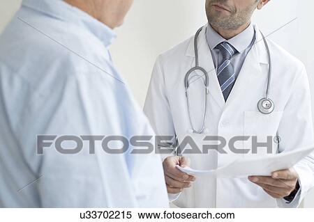 Stock Photography - Male doctor holding medical notes. Fotosearch
