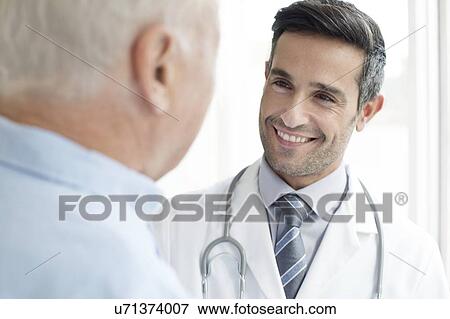 Male doctor smiling at patient View Large Photo Image Stock Photo - Male doctor smiling at patient. Fotosearch