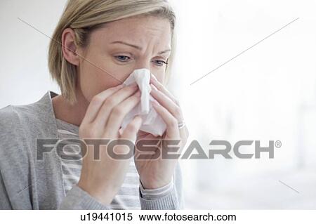 Stock Photography - Mid adult woman blowing her nose. Fotosearch