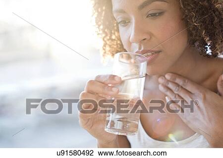 Stock Image - Mid adult woman drinking water. Fotosearch