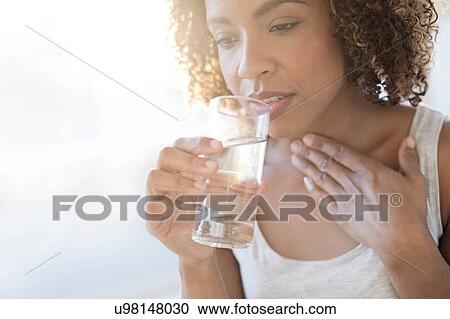 Stock Image - Mid adult woman drinking water. Fotosearch