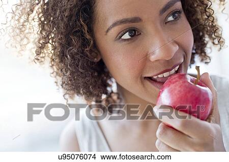 Picture - Mid adult woman eating apple. Fotosearch