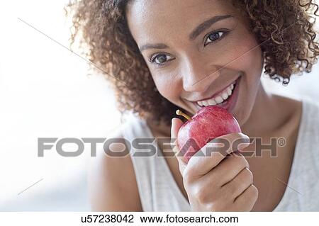Stock Image - Mid adult woman eating apple. Fotosearch