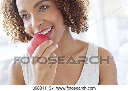 Stock Photo - Mid adult woman eating apple. Fotosearch