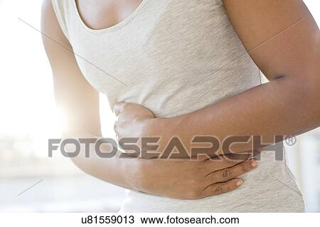 Mid adult woman holding stomach View Large Photo Image Stock Image - Mid adult woman holding stomach. Fotosearch