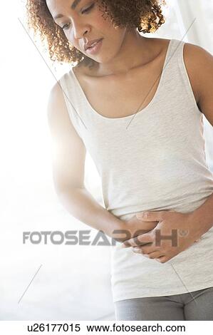 Mid adult woman holding stomach View Large Photo Image Stock Photography - Mid adult woman holding stomach. Fotosearch