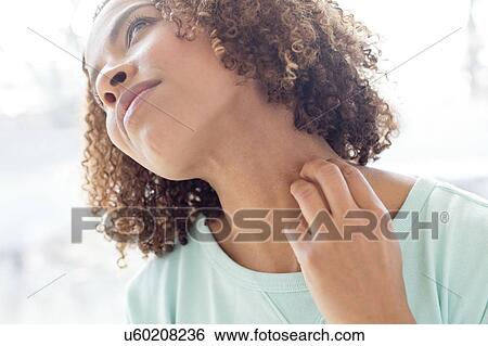 Stock Photograph - Mid adult woman scratching neck. Fotosearch