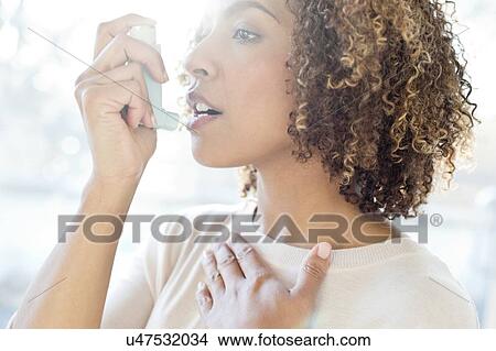 Picture - Mid adult woman using inhaler. Fotosearch