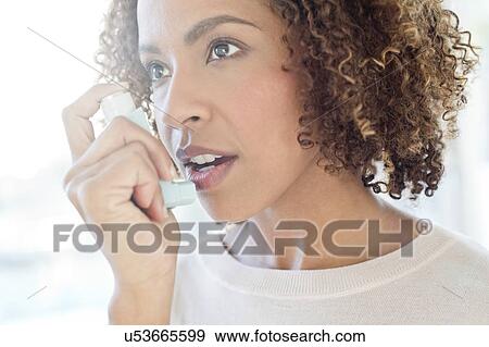 Stock Photo - Mid adult woman using inhaler. Fotosearch