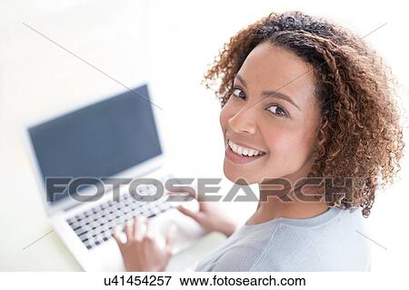Mid adult woman using laptop View Large Photo Image Stock Photo - Mid adult woman using laptop. Fotosearch