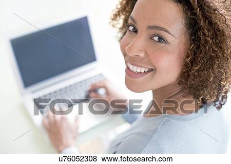 Stock Photo - Mid adult woman using laptop. Fotosearch