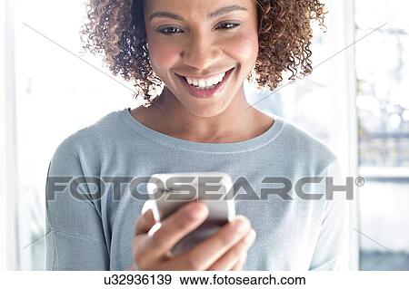 Stock Photo - Mid adult woman using phone. Fotosearch