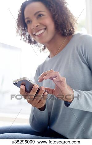 Stock Photo - Mid adult woman using phone. Fotosearch
