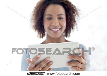 Stock Photo - Mid adult woman using tablet. Fotosearch