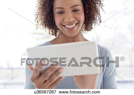 Mid adult woman using tablet View Large Photo Image Stock Photo - Mid adult woman using tablet. Fotosearch