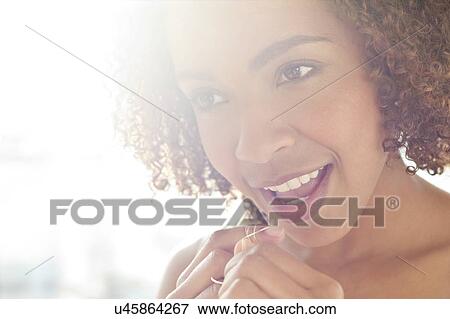 Stock Photo - Portrait of woman flossing teeth. Fotosearch