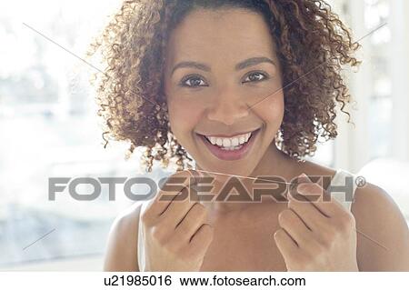 Stock Photograph - Portrait of woman flossing teeth. Fotosearch
