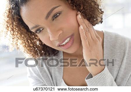 Stock Image - Portrait of woman touching face. Fotosearch