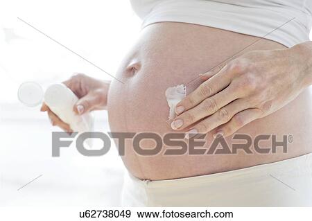 Pregnant woman applying moisturiser to her tummy View Large Photo Image Stock Photo - Pregnant woman applying moisturiser to her tummy. Fotosearch